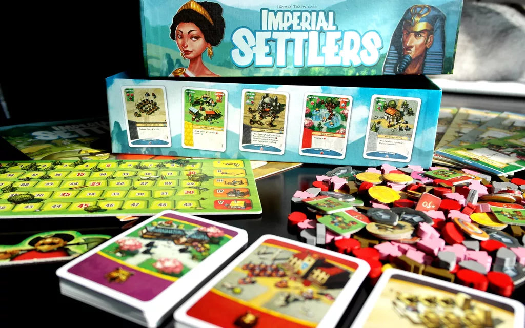 Board game set with cards and pieces on a table, featuring 'Imperial Settlers' branding.