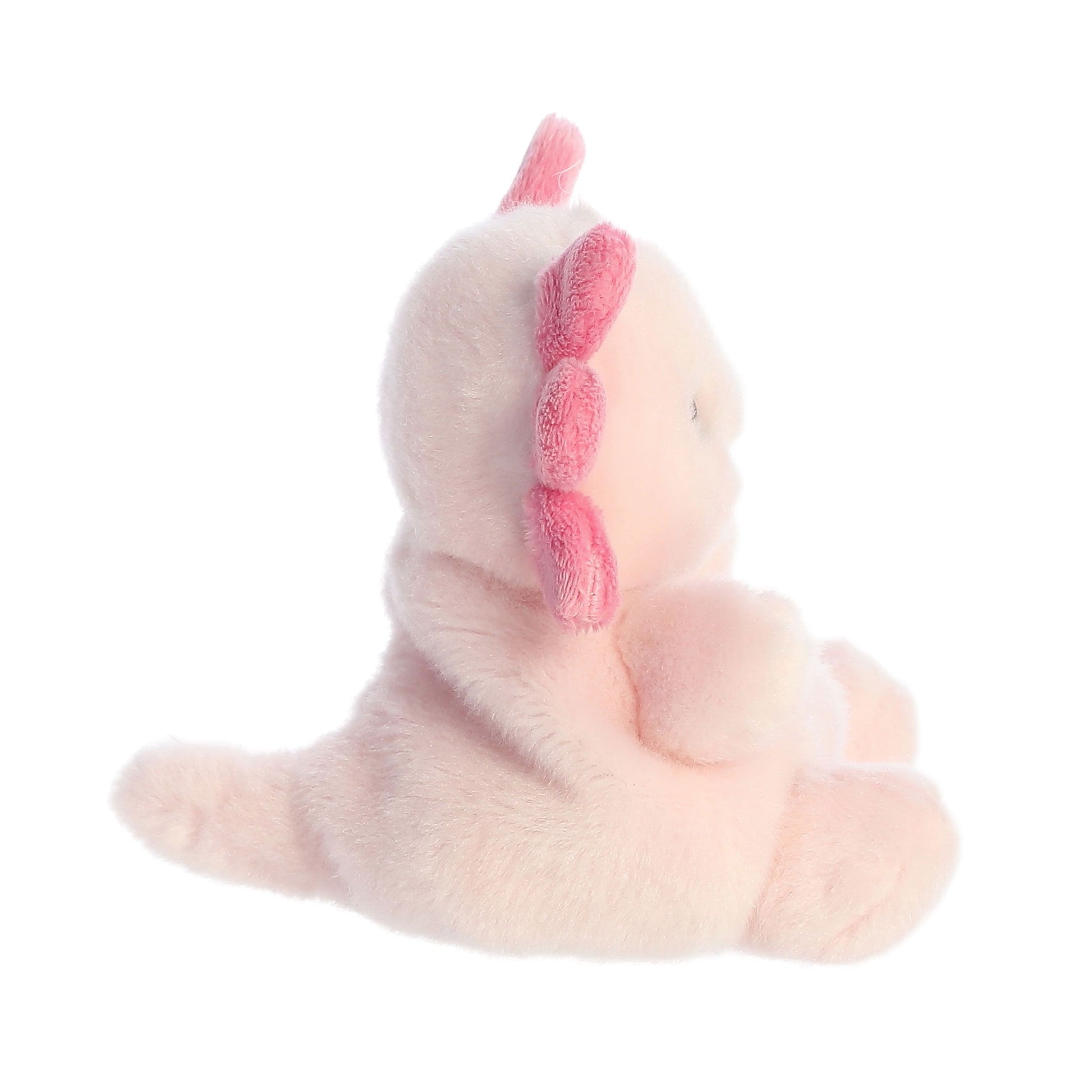 A side view of the Twice as Sweet Palm Pal Ax Axolotl plush, featuring a round body, tail, and darker pink accents on its back and head, sitting upright against a white background.