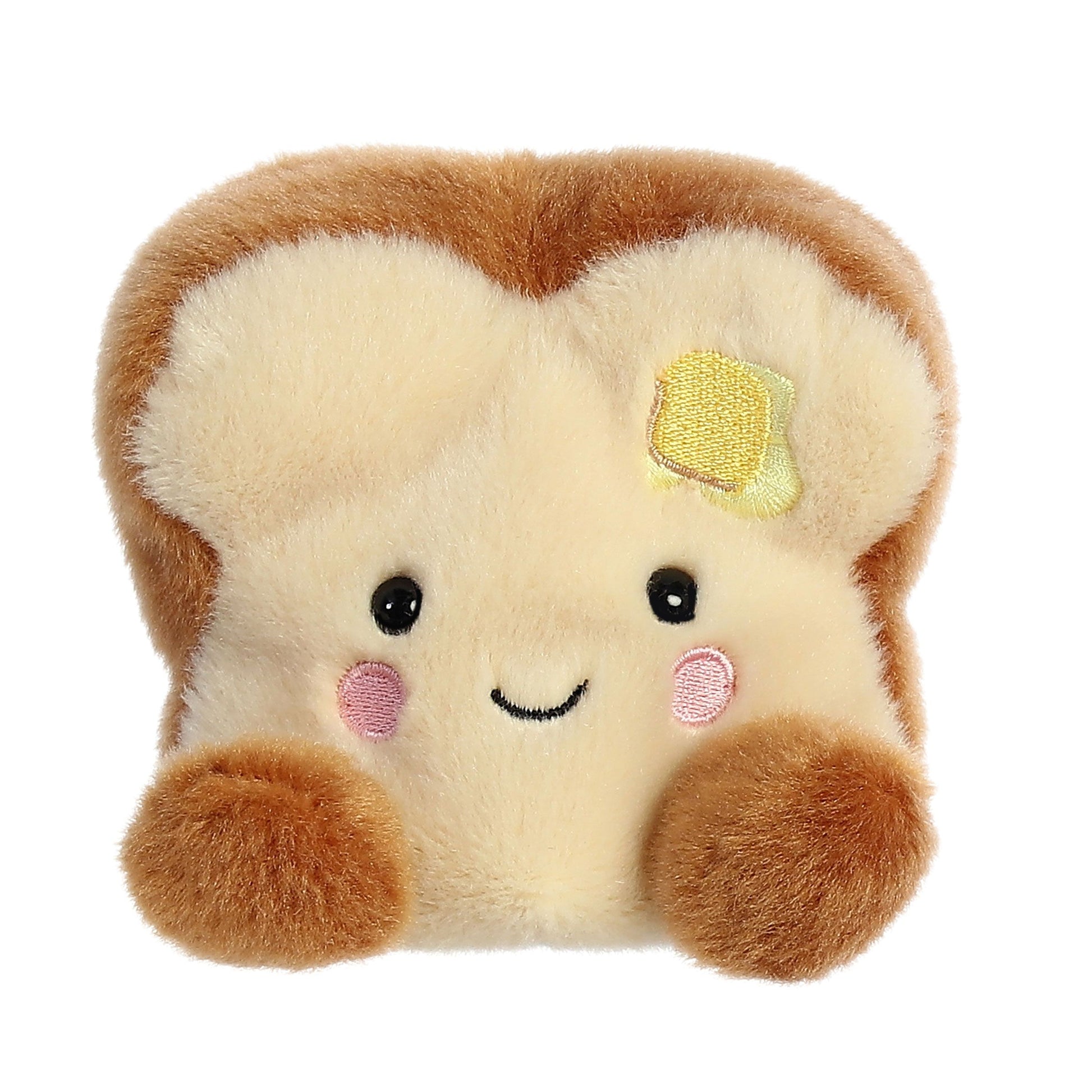 The Palm Pal Buttery Toast by Twice as Sweet is a palm-sized plush shaped like a bread slice, featuring soft brown and cream colors, a smiling face with pink cheeks, black eyes, and a cute yellow butter patch.