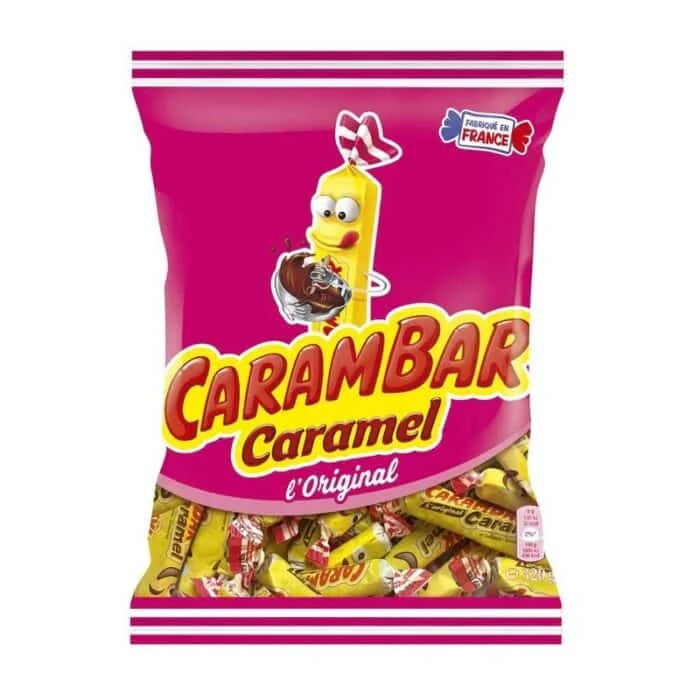 A bag of Twice as Sweet Carambar Caramel (France) sweets, with pink and yellow packaging featuring a cartoon caramel stick holding chocolate and a “Made in France” label. Enjoy this iconic chewy caramel treat!.