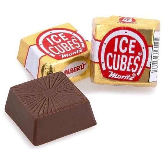 Three pieces of Twice as Sweet Chocolate Ice Cube (Germany): two wrapped in gold foil with red and white labels, and one unwrapped to show a textured dark brown square—an irresistibly creamy chocolate treat.
