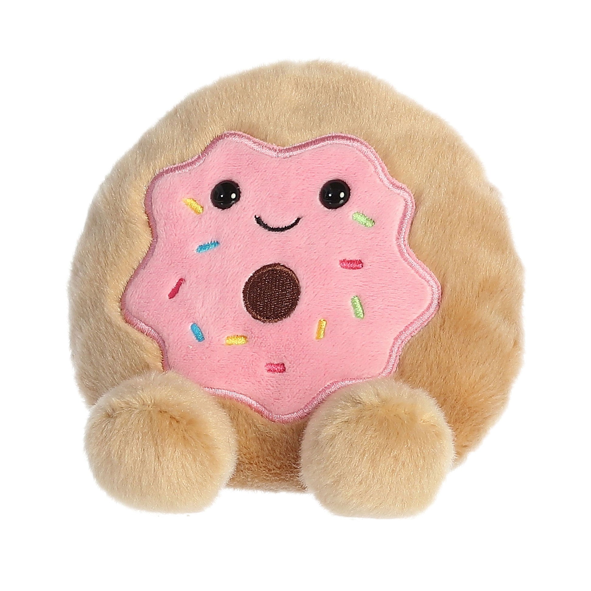 Meet Palm Pal Claire Donut by Twice as Sweet, a plush toy shaped like a donut with pink frosting, colorful sprinkles, a smiling face, and two round fluffy feet.
