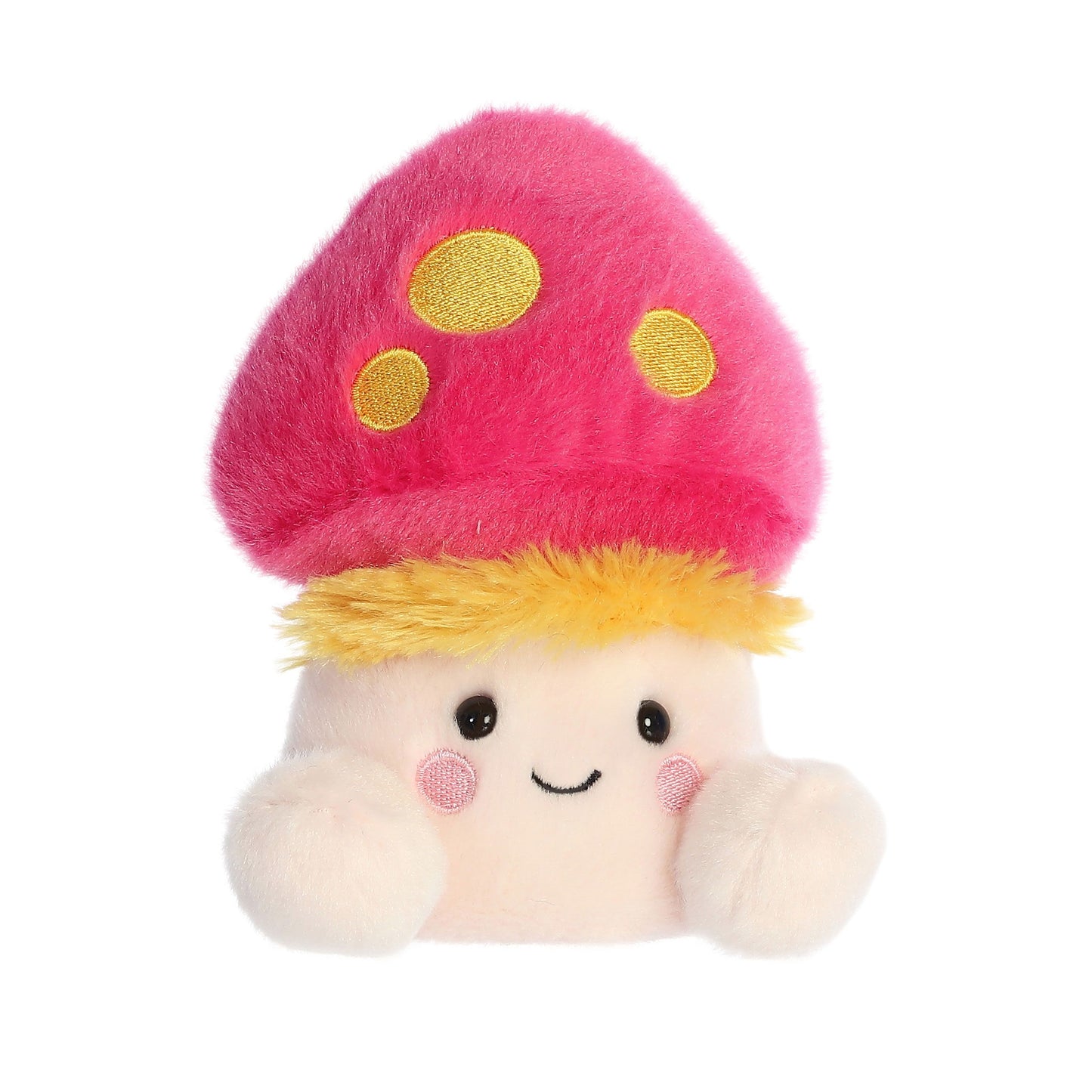 The Twice as Sweet Palm Pal Favio Fluffy Mushroom is a whimsical plush shaped like a smiling storybook character, featuring a pink cap with yellow spots, yellow fringe, rosy cheeks, and small arms.