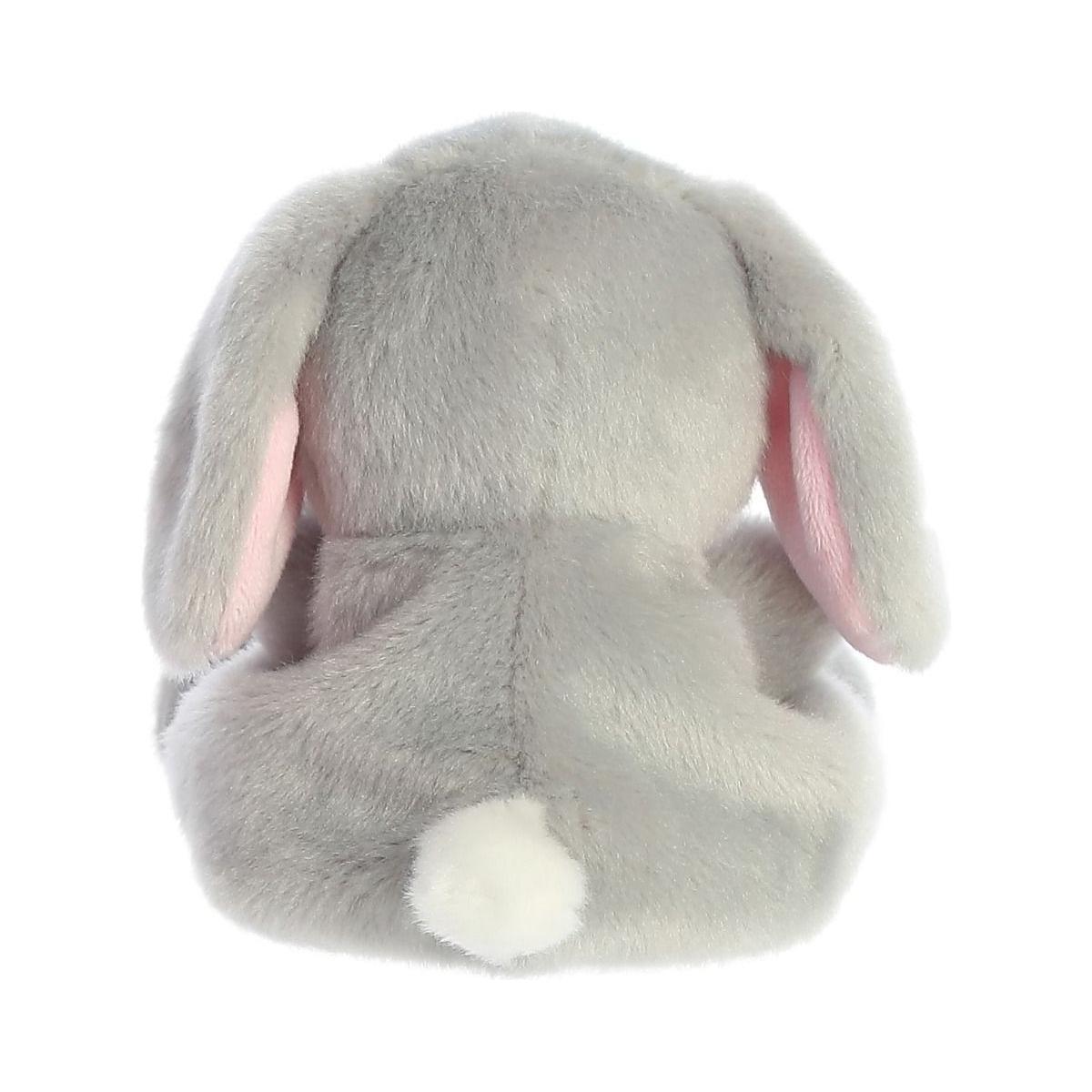The Twice as Sweet Palm Pal Pebbles Bunny is pictured from the back, featuring soft slate-grey fur, pink-lined floppy ears, and a small white tail.