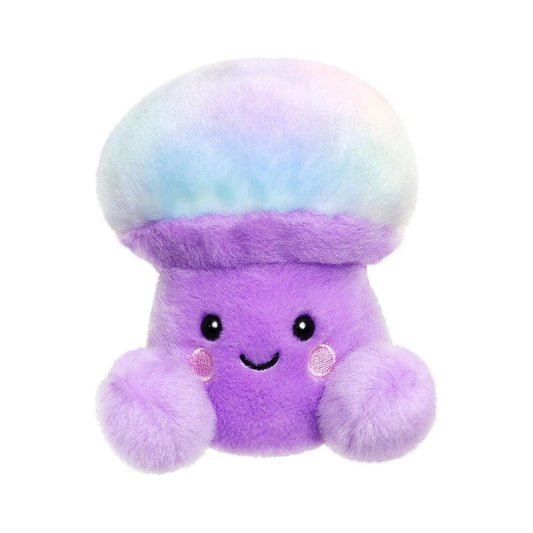 The Palm Pal Lunette Mushroom by Twice as Sweet is a whimsical plush toy with a pastel rainbow cap, soft purple body, blushing cheeks, and two fuzzy hands. It features a smiling mushroom design on a plain white background.