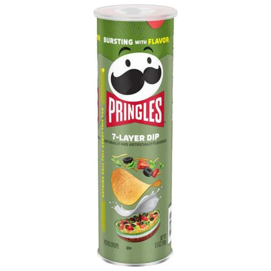A tall green can of Twice as Sweet Pringles 7-Layer Dip 158g (USA) party snack features crisps topped with tomatoes, olives, cheese, and the mustachioed Pringles mascot.
