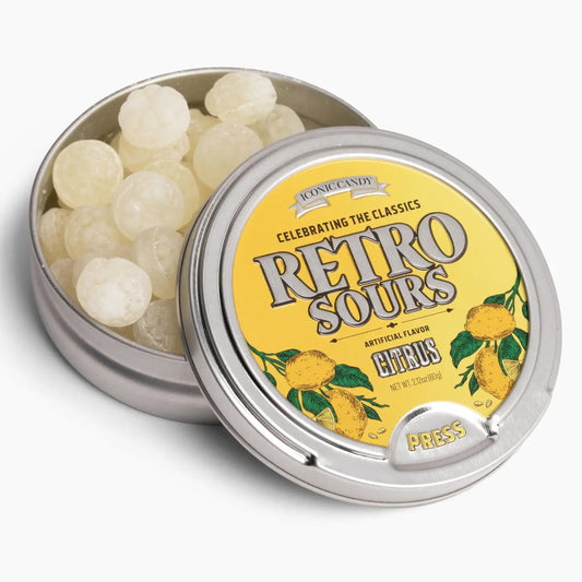 An open Twice as Sweet Retro Sours Citrus 60g (USA) tin with a yellow lemon-themed lid reveals white round sour candies inside. This classic American treat comes in a metallic tin with a press-top lid.
