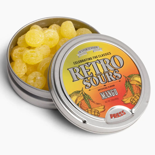 A round tin of Twice as Sweet Retro Sours Mango 60g (USA) sour candy, with a partially open lid featuring mango images and bold “Retro Sours Mango” text on an orange-yellow gradient—celebrating this classic American treat.