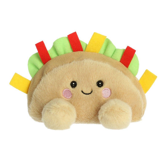 The Twice as Sweet Palm Pal Fiesta Taco is a colorful, soft plush shaped like a taco with a smiling face, pink cheeks, and green, red, and yellow felt toppings—perfect as a cheerful party companion!.