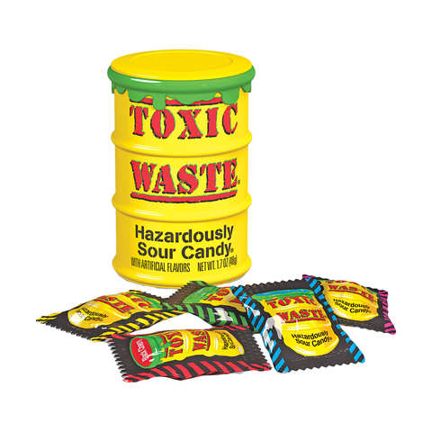 A yellow, barrel-shaped Twice as Sweet Toxic Waste Hazardously Sour Candy 48g (USA) container with Hazardously Sour label and green slime detail is surrounded by colorful, individually wrapped extreme sour candies.