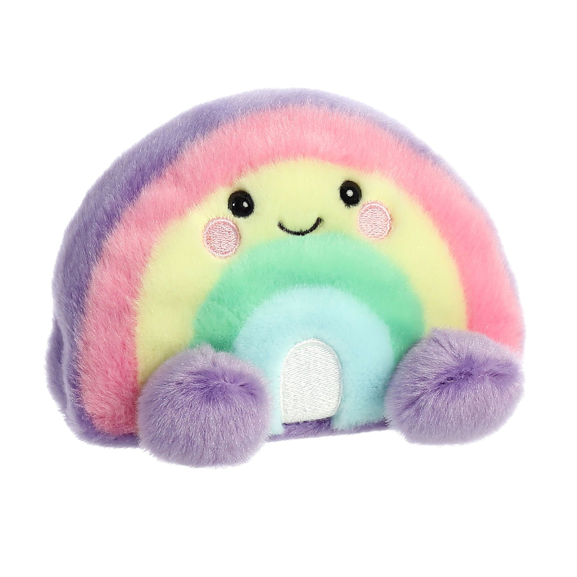 The Twice as Sweet Palm Pal Vivi Rainbow is a plush toy shaped like a smiling rainbow with pastel stripes in purple, pink, yellow, green, and blue, rosy cheeks, and fluffy purple feet—a cheerful stuffed animal to brighten any day.