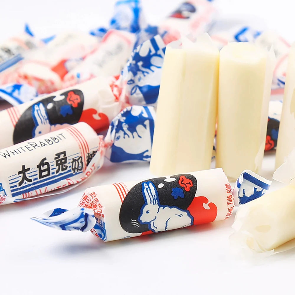 Unwrapped and wrapped Twice as Sweet White Rabbit Creamy Candy 227g (China) are displayed on a white surface. The wrappers show a white rabbit illustration with red, blue, and black accents, along with Chinese characters.